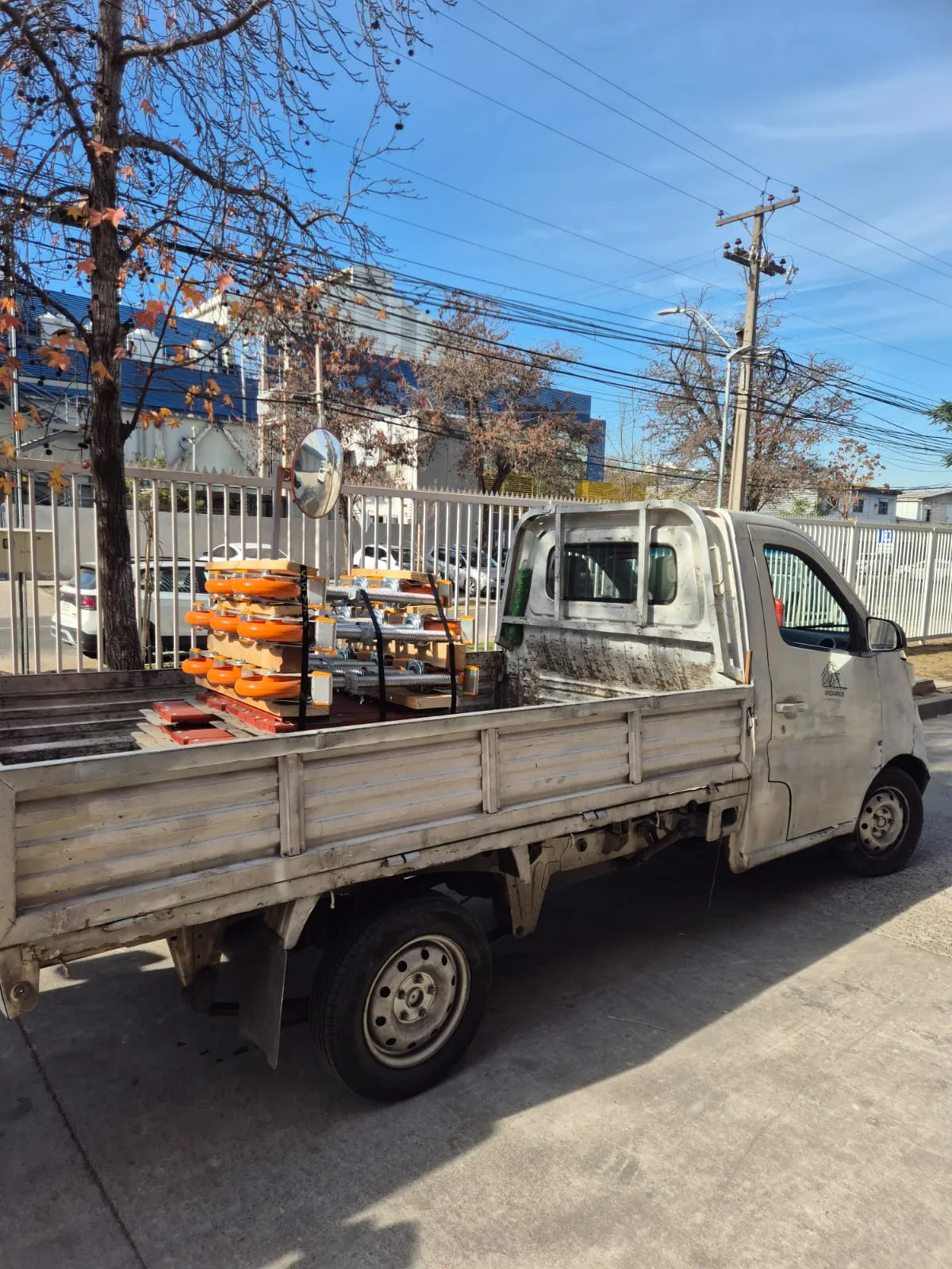 Camión de despacho con ruedas y componentes de andamio Layher cargados en plancha