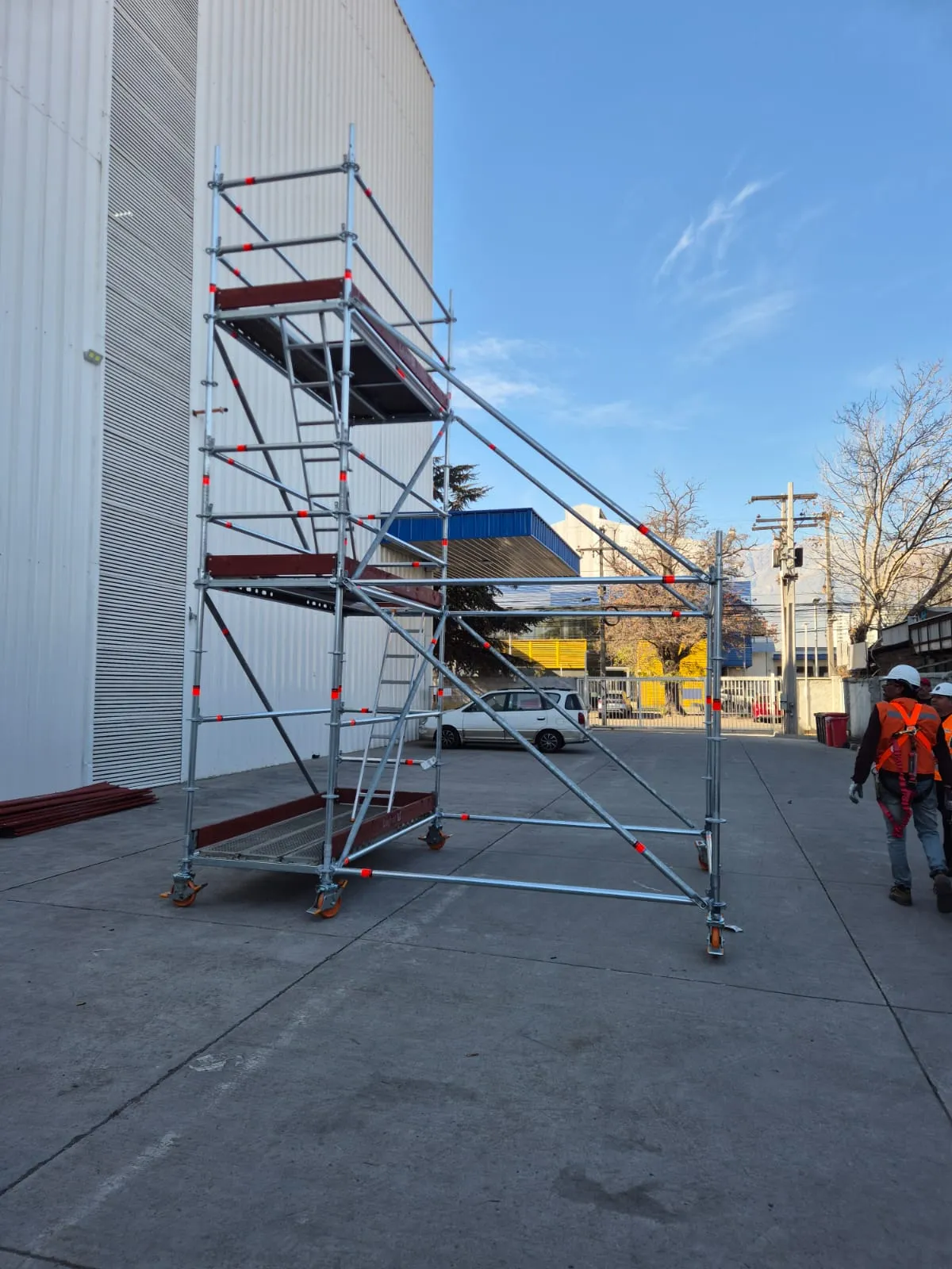 Torre de andamio Layher de gran altura en patio industrial, vista lateral con escalera interna