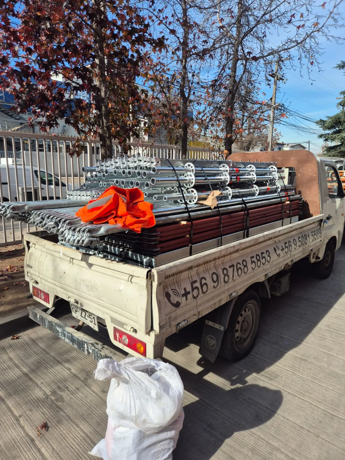 Camión con tubos y marcos de andamio Layher asegurados en plancha para traslado a obra